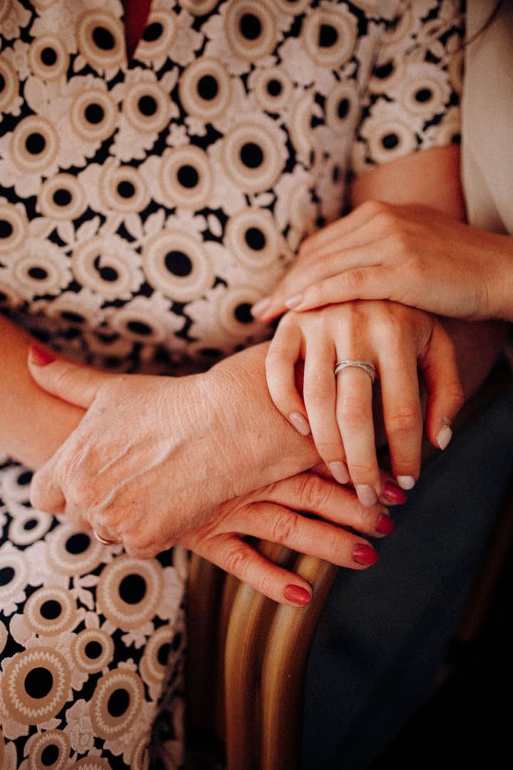 A younger hand resting on the hands of an older woman with freshly polished nails